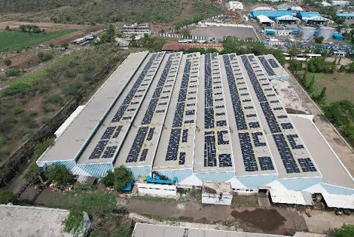 Industrial rooftop solar panels installed on a large manufacturing facility, showcasing commercial renewable energy infrastructure
